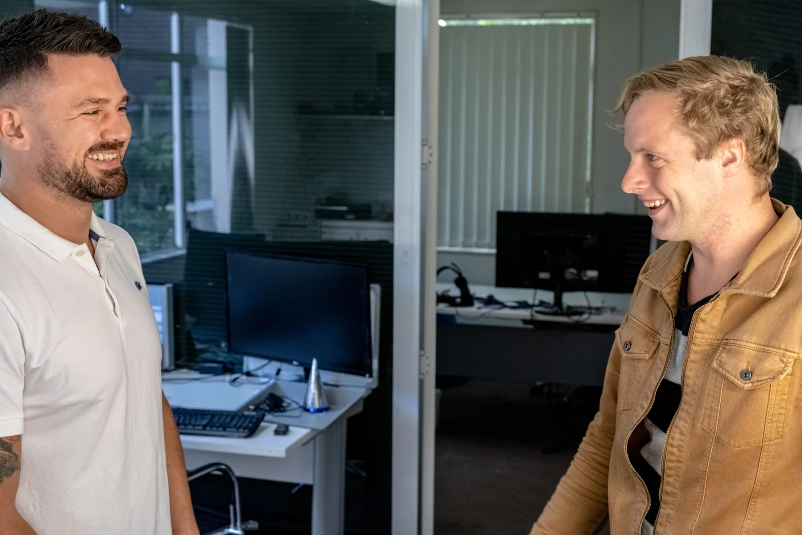 Two men smiling and talking in an office