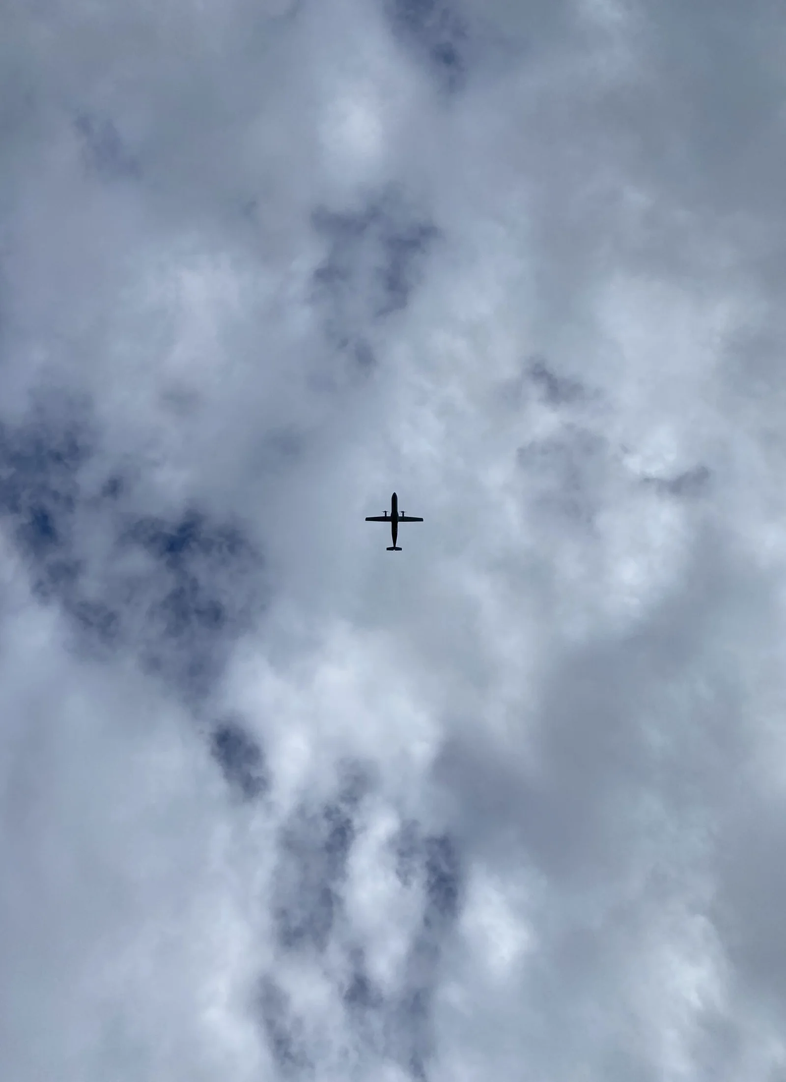 Silhouette of airplane flying through dramatic cloudy sky