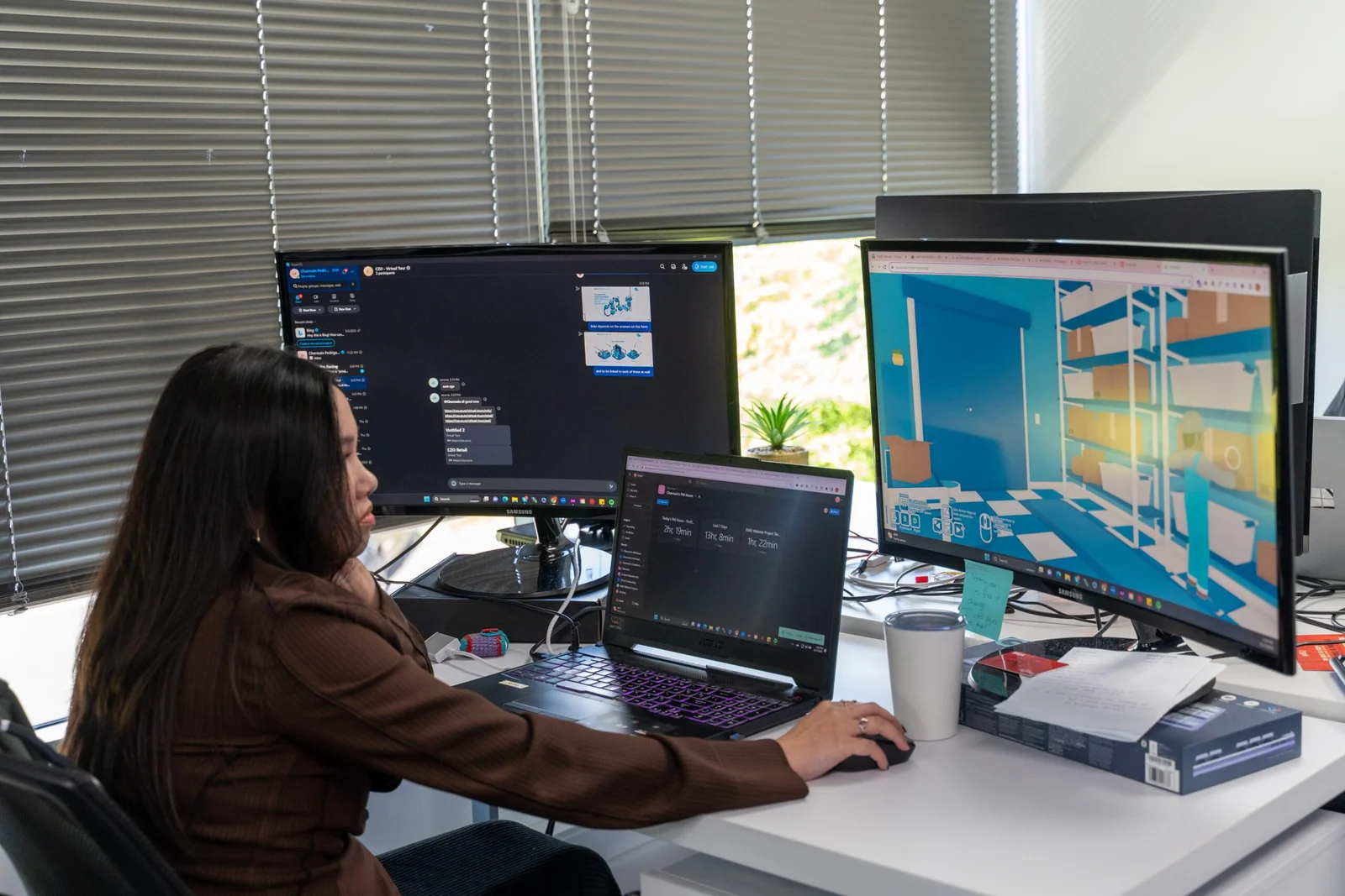 Woman working at multi-monitor computer setup with 3D modeling software