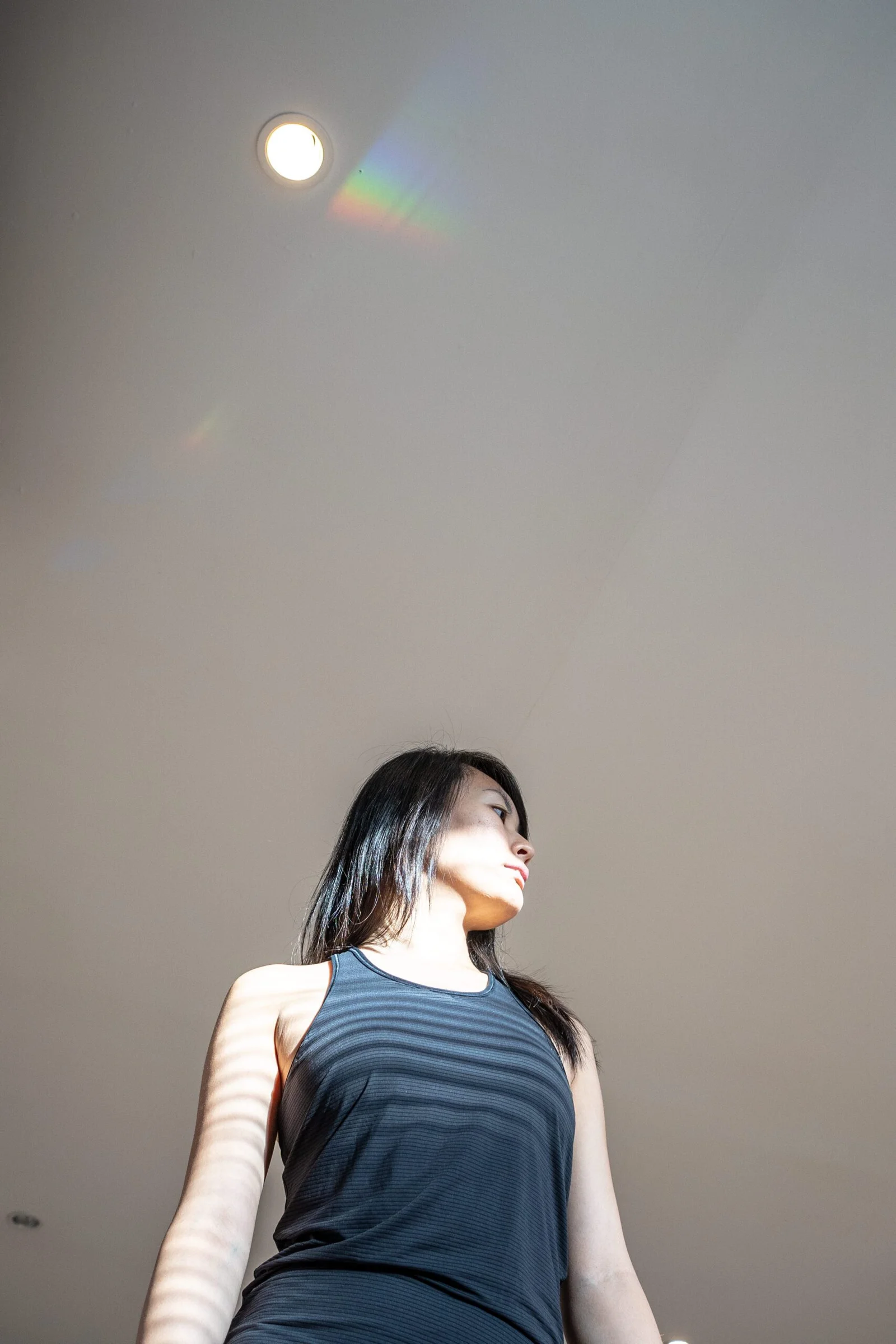 Low-angle shot of a woman with a rainbow light reflection on the ceiling