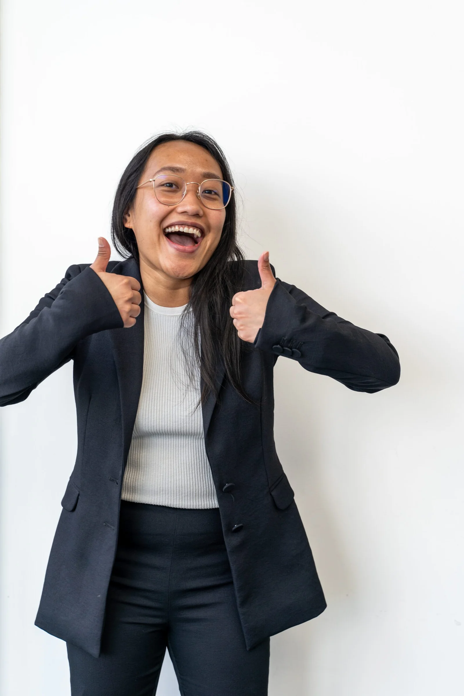 Smiling woman with glasses giving two thumbs up