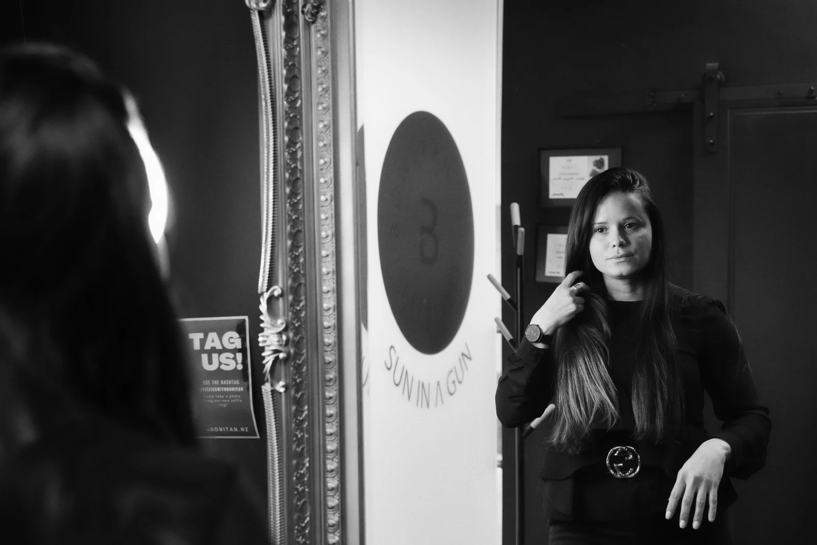 Black and white image of a woman looking at her reflection in a mirror