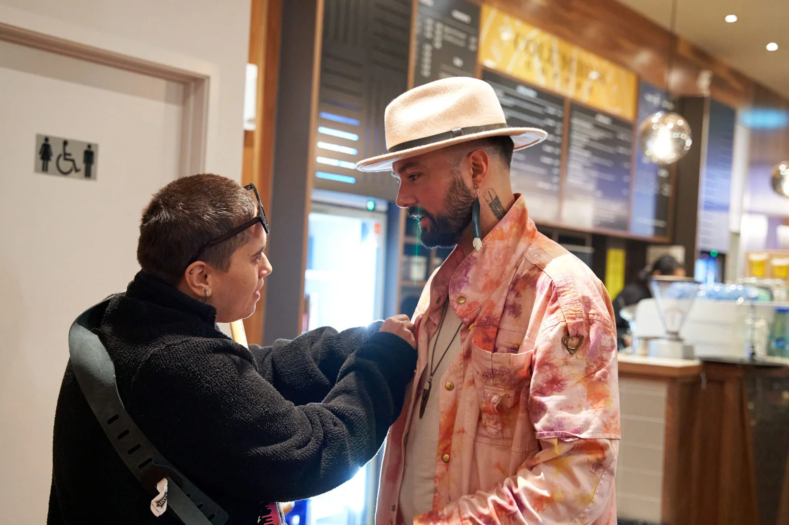 Two people in styling context, one adjusting the other's clothing