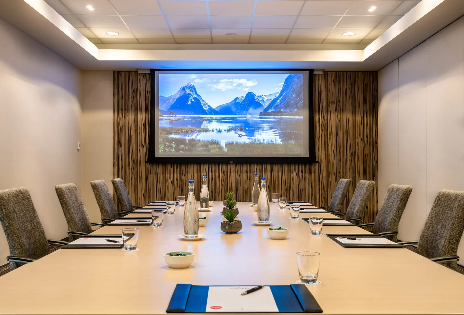 Professional conference room with mountain landscape screen and meeting setup