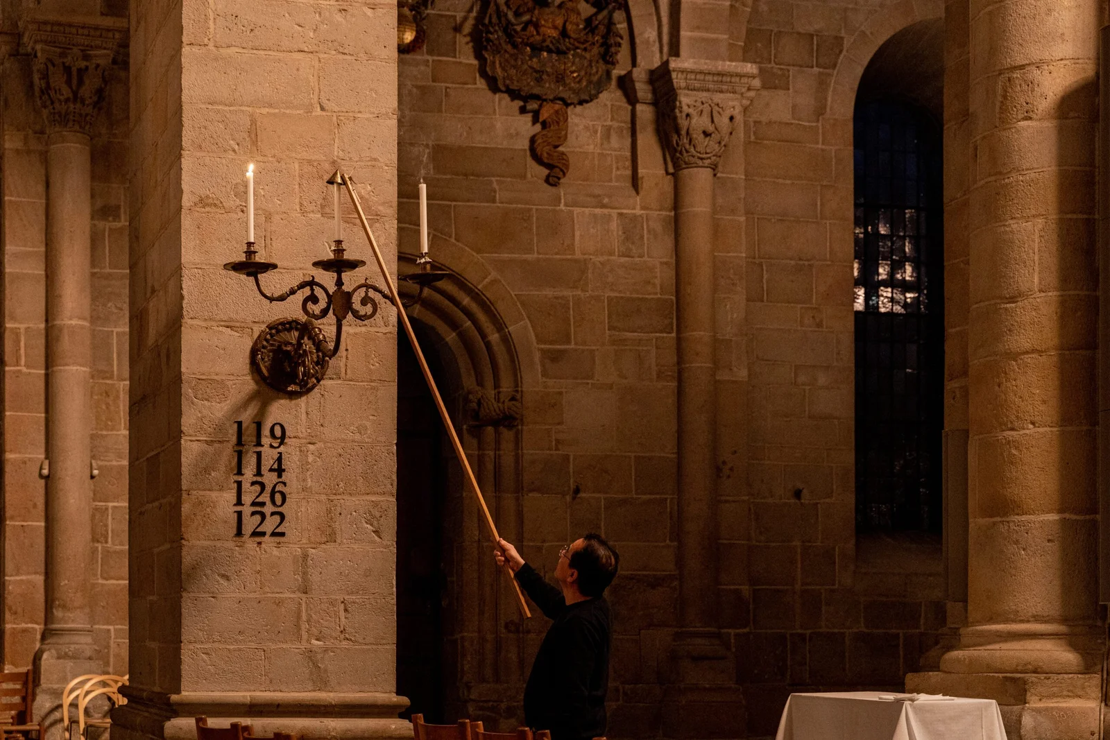 Person lighting candles in historic stone church interior