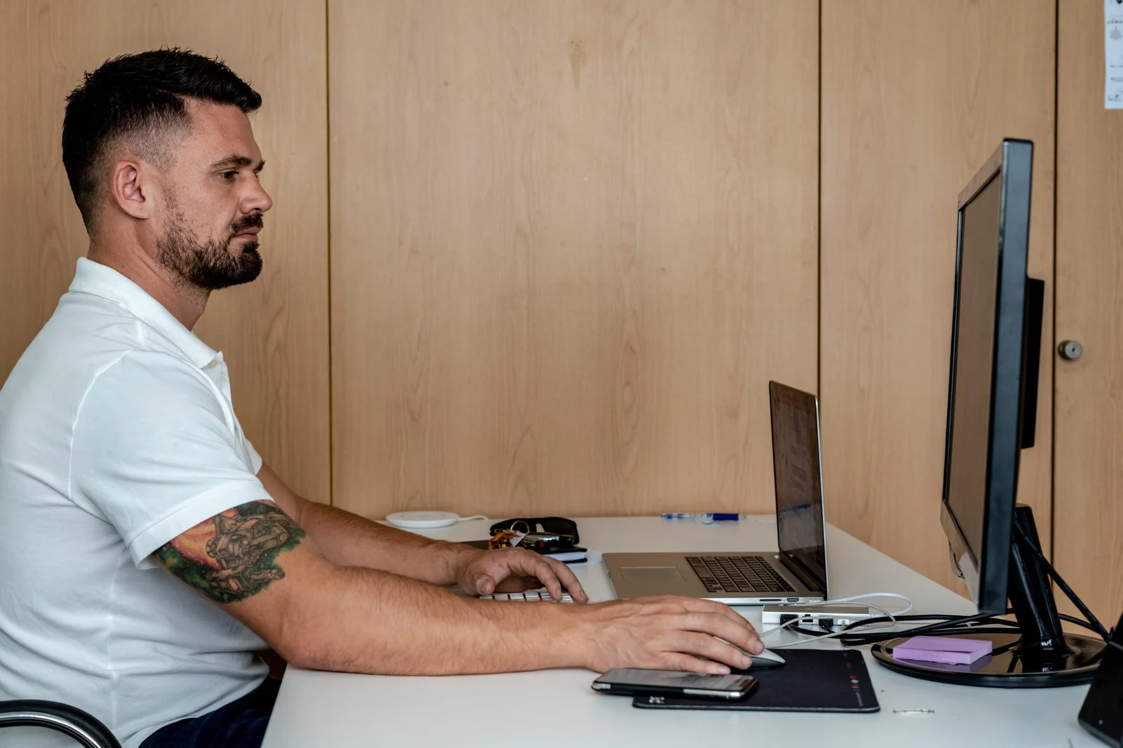 Man with beard and tattoo working at an office desk