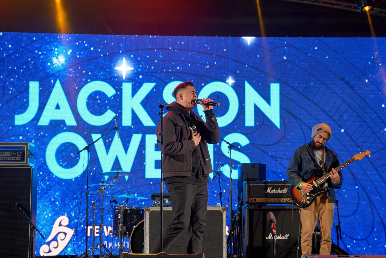 Male singer performing on stage with 'JACKSON OWENS' on screen