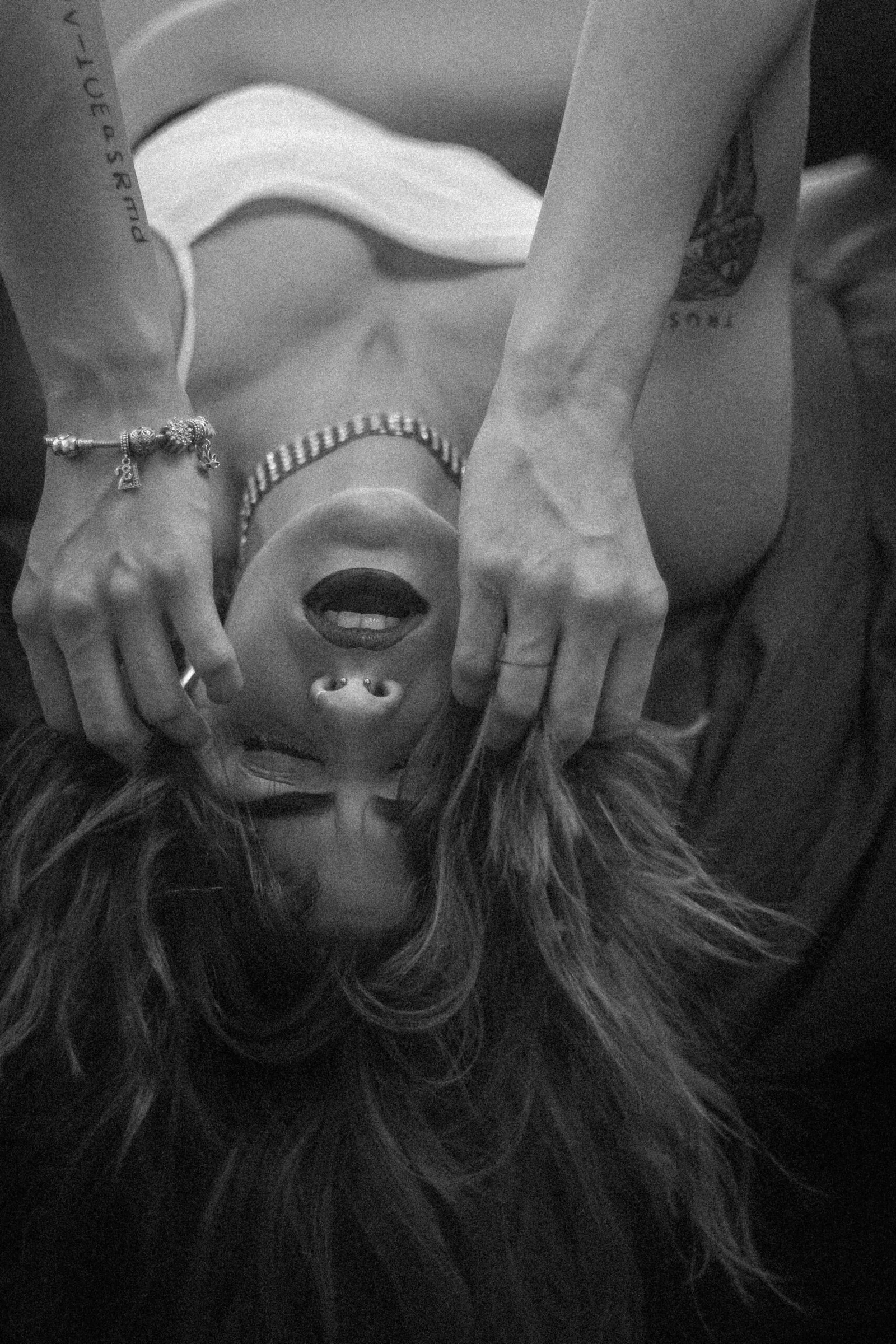 Close-up of a woman lying down with hands near her head (black and white)