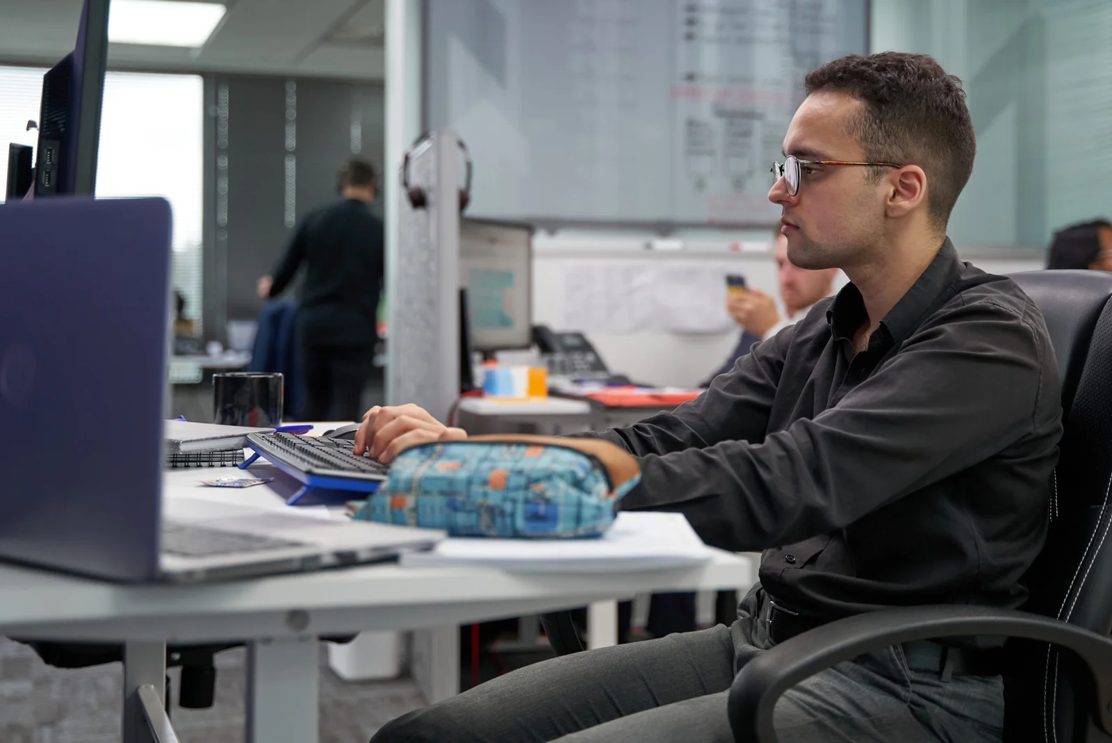 Man with glasses working on a computer at an office desk
