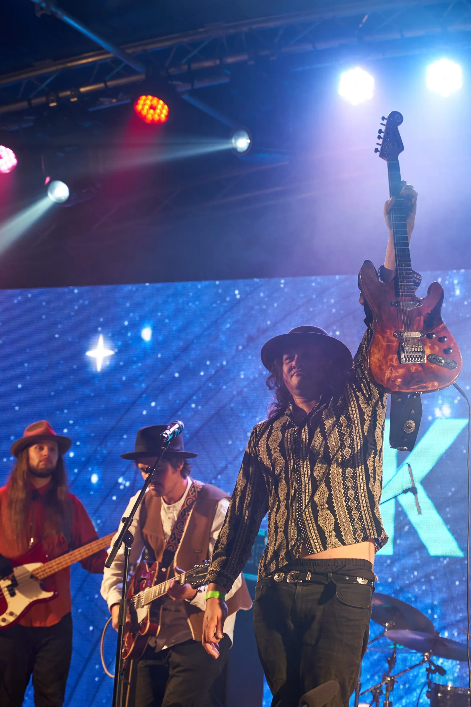 Musician holding guitar above his head on stage