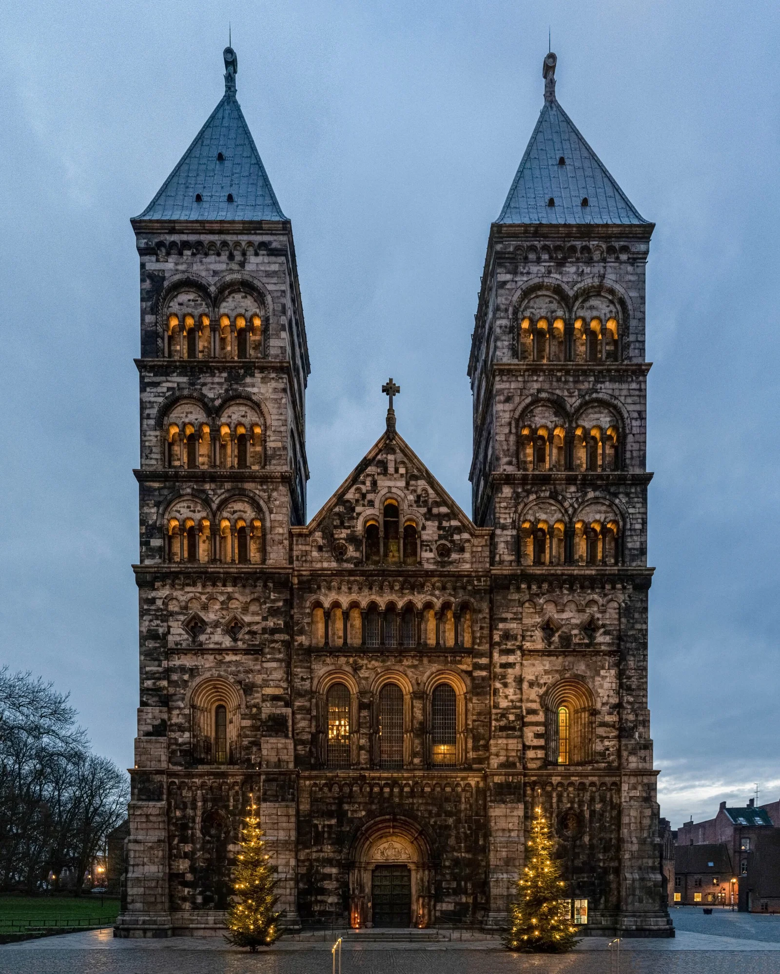 Grand stone cathedral with two towers and Christmas trees