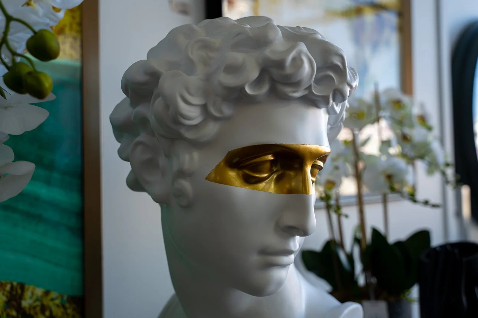 White classical bust with a modern gold mask over its eyes