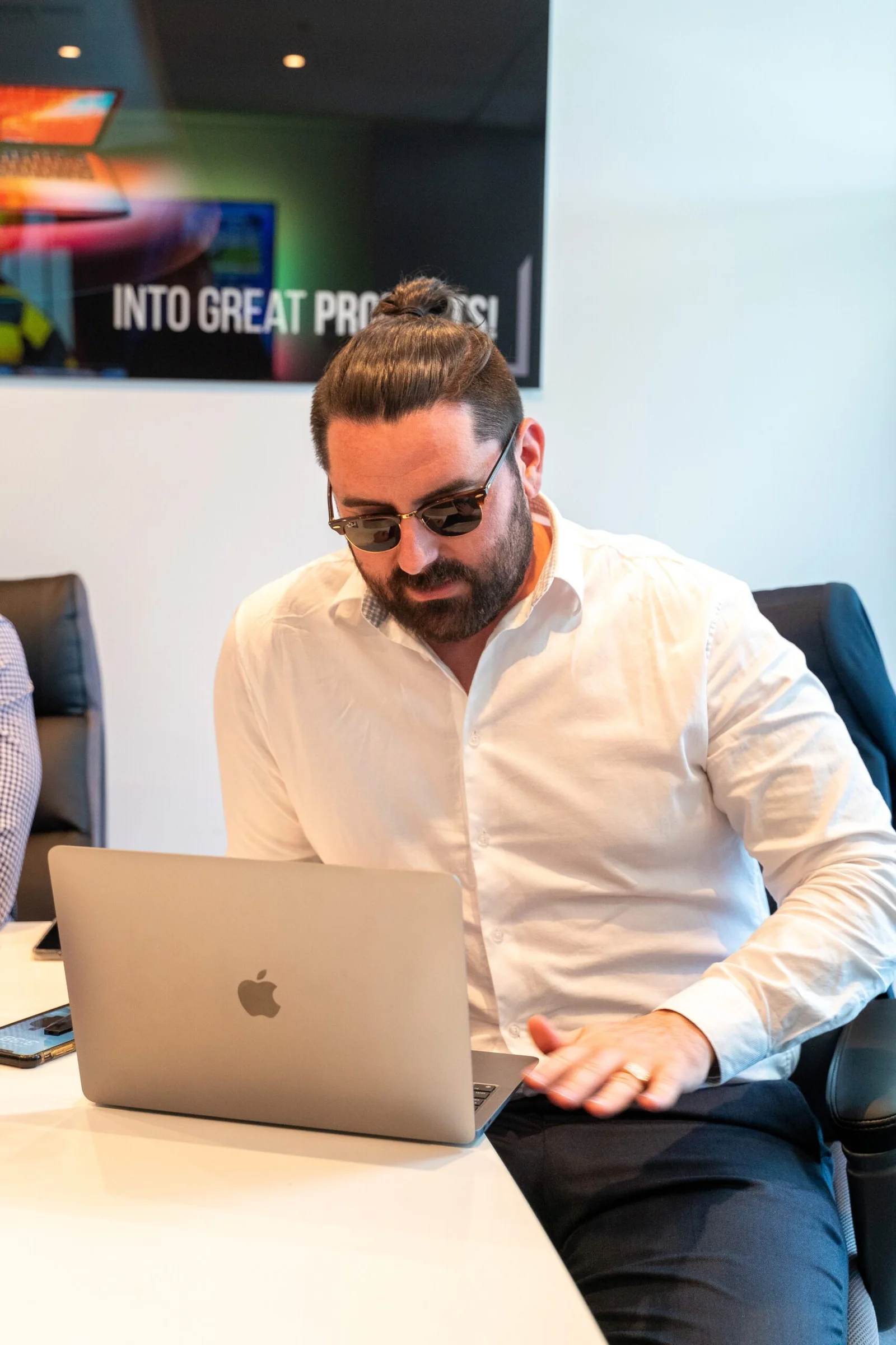 Man with beard and sunglasses looking at a MacBook laptop