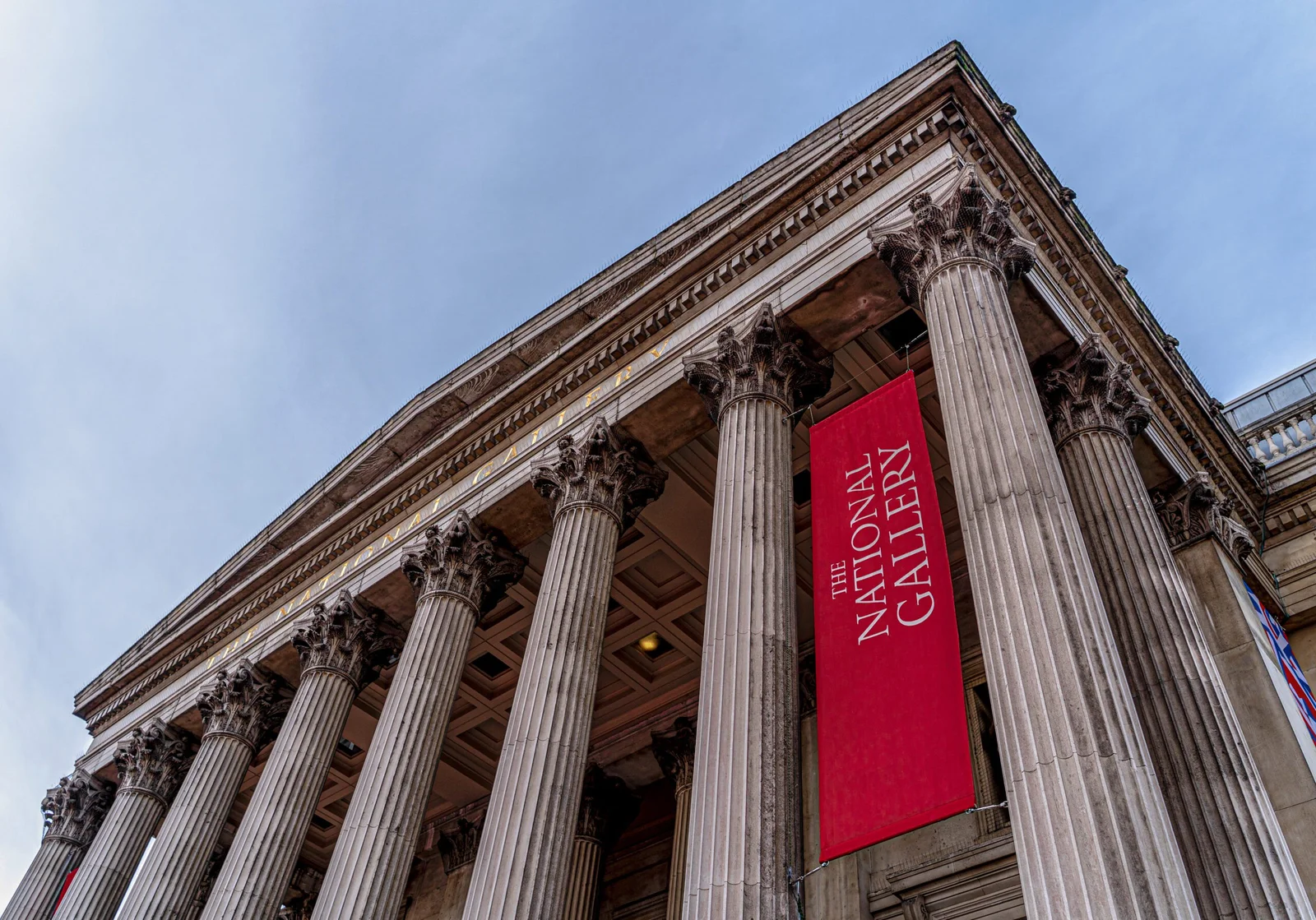 Low-angle view of The National Gallery building with columns and a red banner