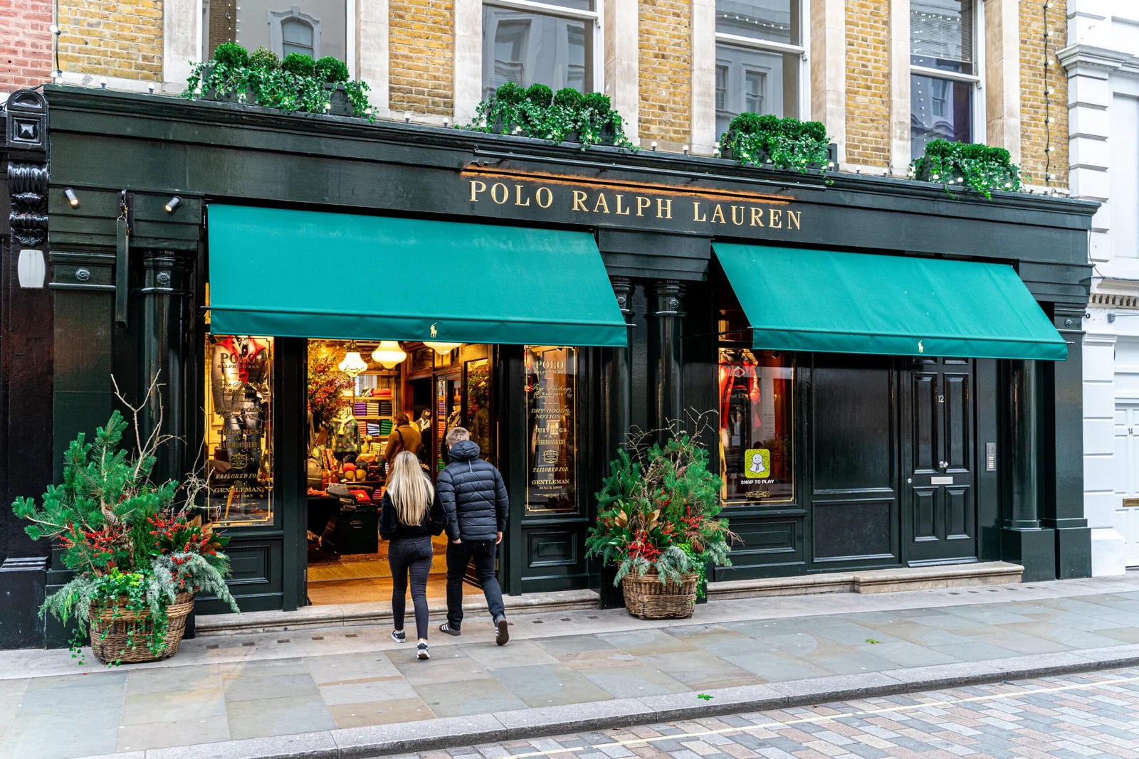 Two people walking towards the entrance of a Polo Ralph Lauren store