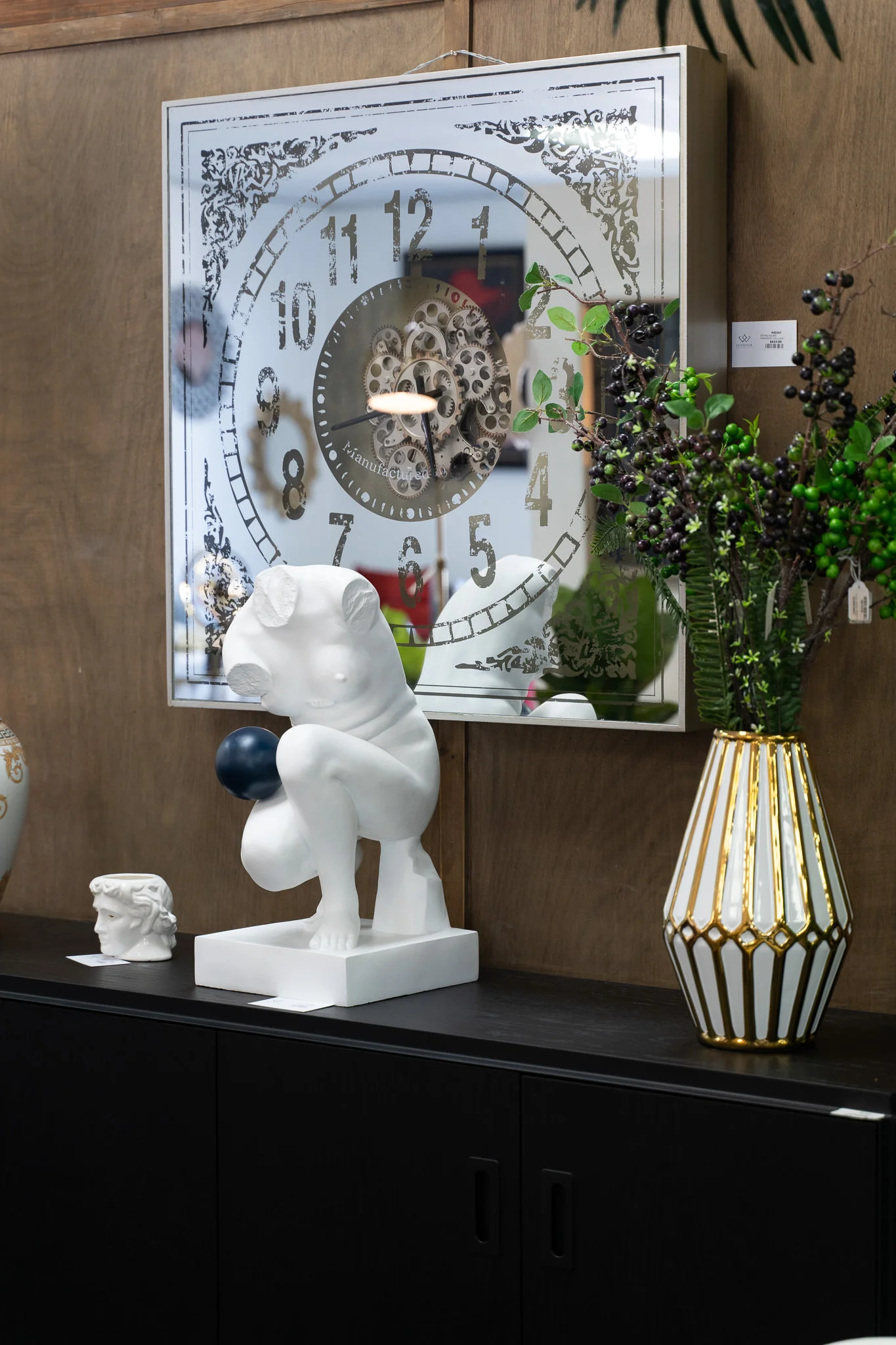 Interior design scene with white decorative sculpture, ornate wall clock, and geometric lamp